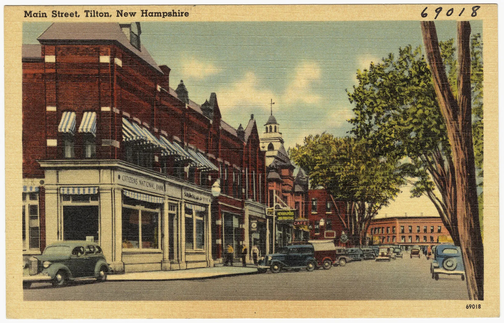 A colored postcard of a wide street bordered by multi-storied buildings. Multi-colored cars can be seen traveling down both sides of the street. The title of the postcard, located in the upper left-hand corner, reads "Main Street, Tilton, New Hampshire."