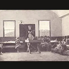 Old classroom with a teacher standing in front of children seated on benches.