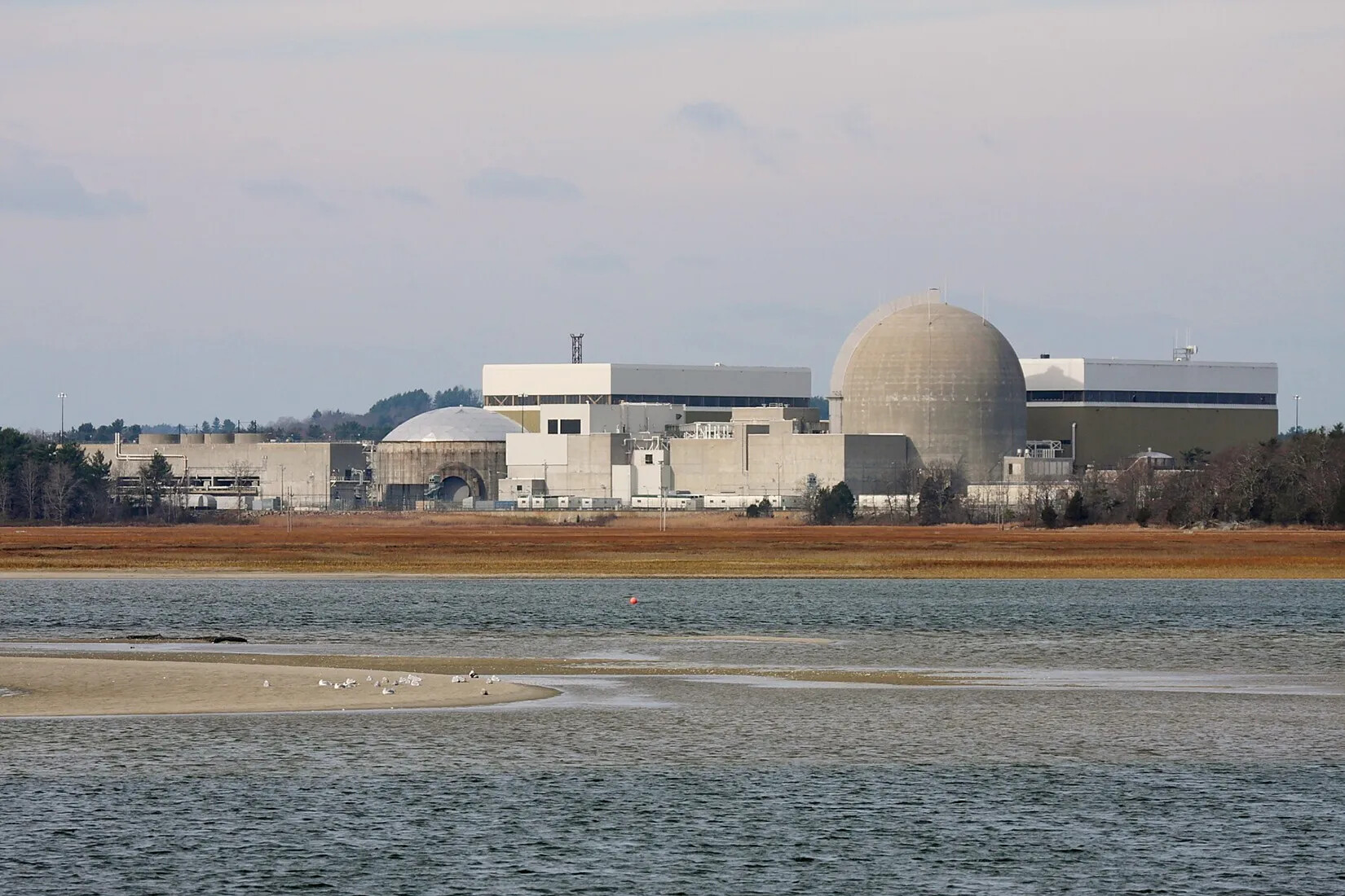 A colored photograph of several multi-storied buildings and domed buildings next to a large body of water.