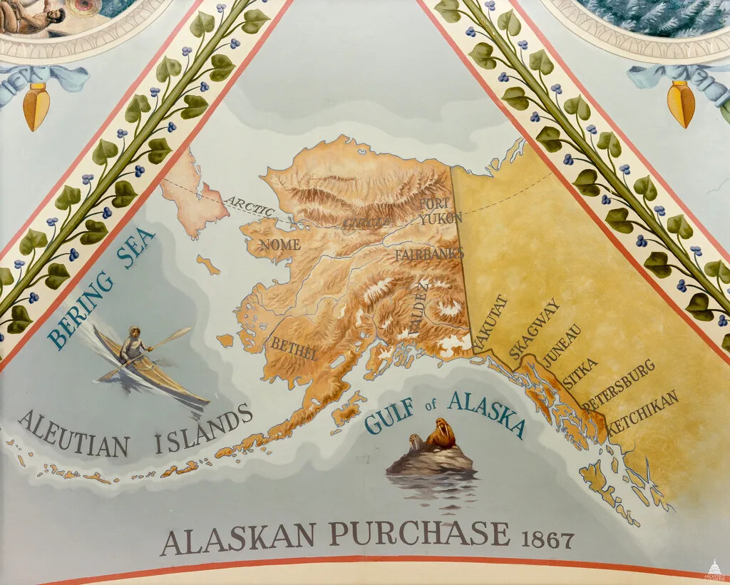 A decorative map shows a close up of the Alaskan purchase connected to western Canada. Alaska is dark orange and shows elevation lines. Canada is dark yellow and bodies of water are various shades of blue. In the water, an Eskimo hunts in a kayak near a seal and walrus. On the map various important towns in Alaska are labeled. The Gulf of Alaska, Bering Sea, and Aluetian Islands are labeled. The map is titled "Alaskan Purchase 1867."