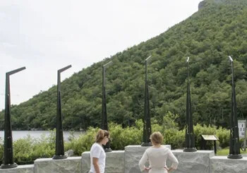 Two people at Profile Plaza with mountain and lake in the background.