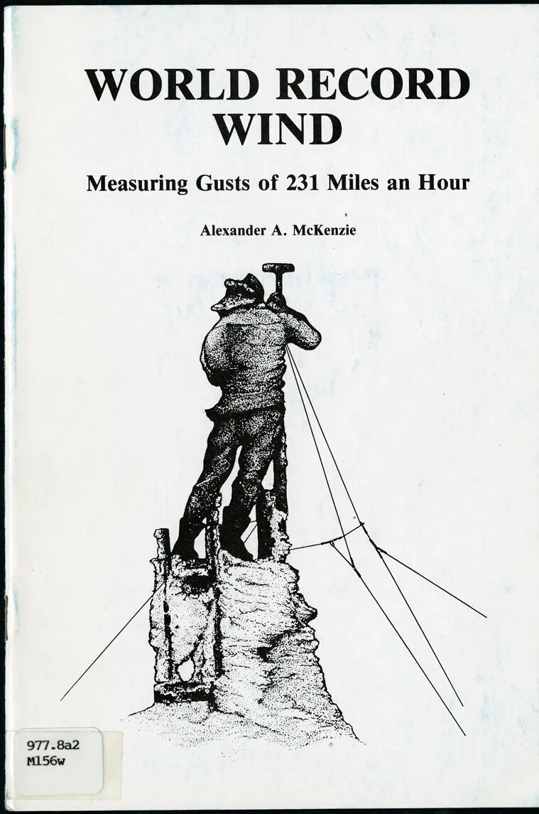A page shows a black and white drawing of a standing man with his back to the viewer, holding onto a pole. The pole is secured to the base with lines, and has a small rectagular box on top. The man wears winter clothing, and is standing on a narrow tower. The text reads "WORLD RECORD WIND/ Measuring Gusts of 231 Miles an Hour/ Alexander A. McKenzie."