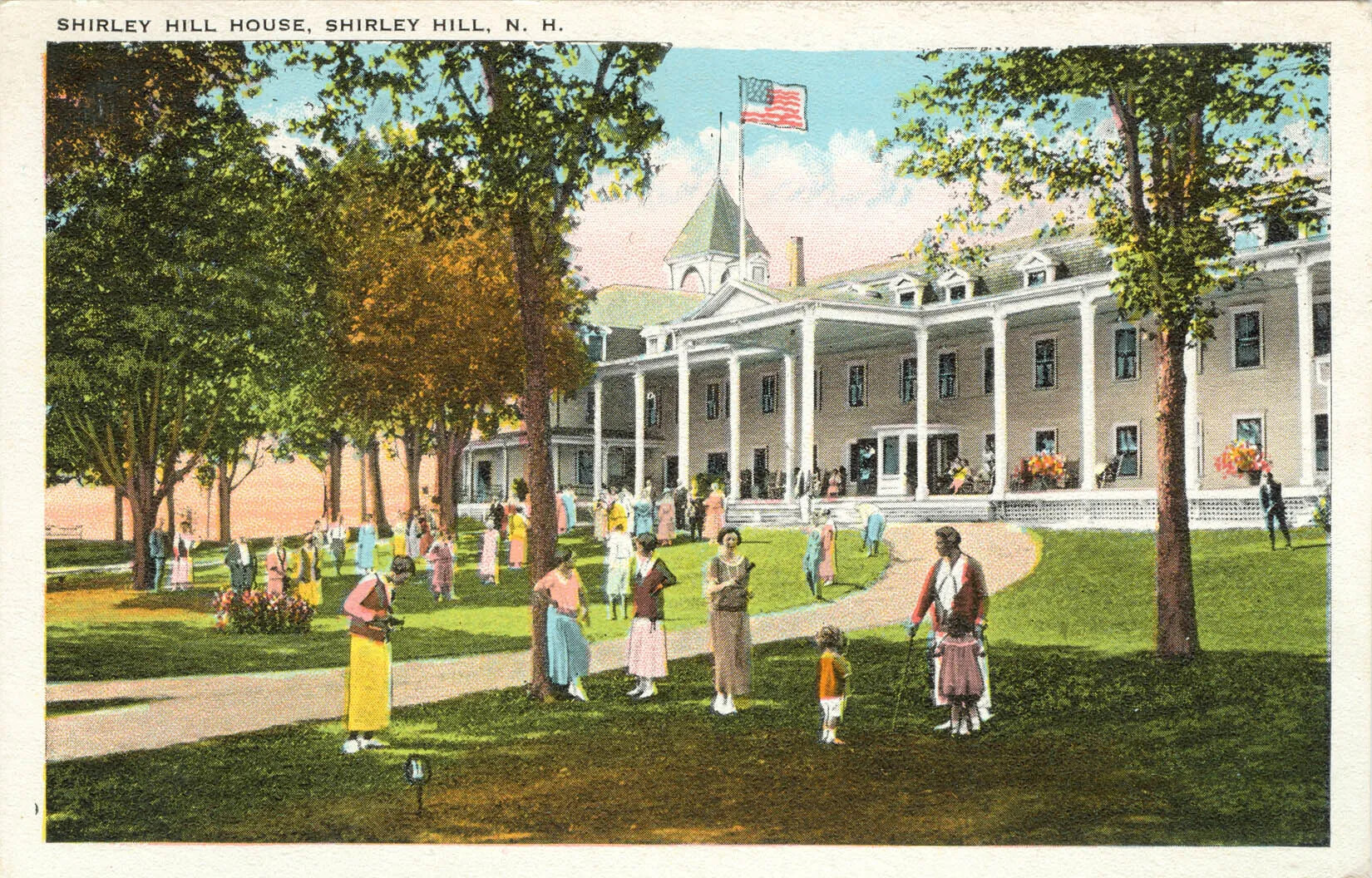 A colored postcard of a group of people clustered in front of a three-storied building. The building has a tower and large front porch, above which an American flags flies from a tall pole. The title of the postcard, located in the upper left-hand corner, reads: "SHIRLEY HILL HOUSE, SHIRLEY HILL, N. H."