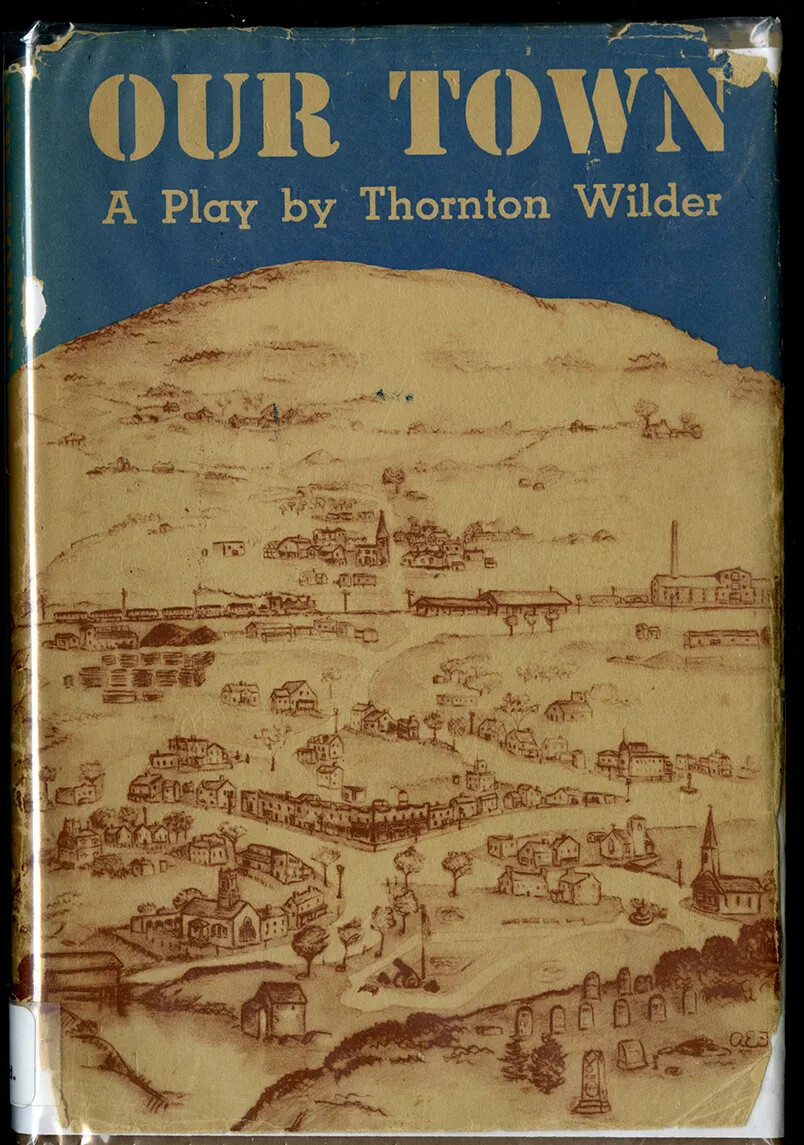 A colored book cover. The title of the book, located along the upper border, reads "OUR TOWN/A Play by Thornton Wilder." Beneath the title is a drawing of a bird's-eye view of a town.