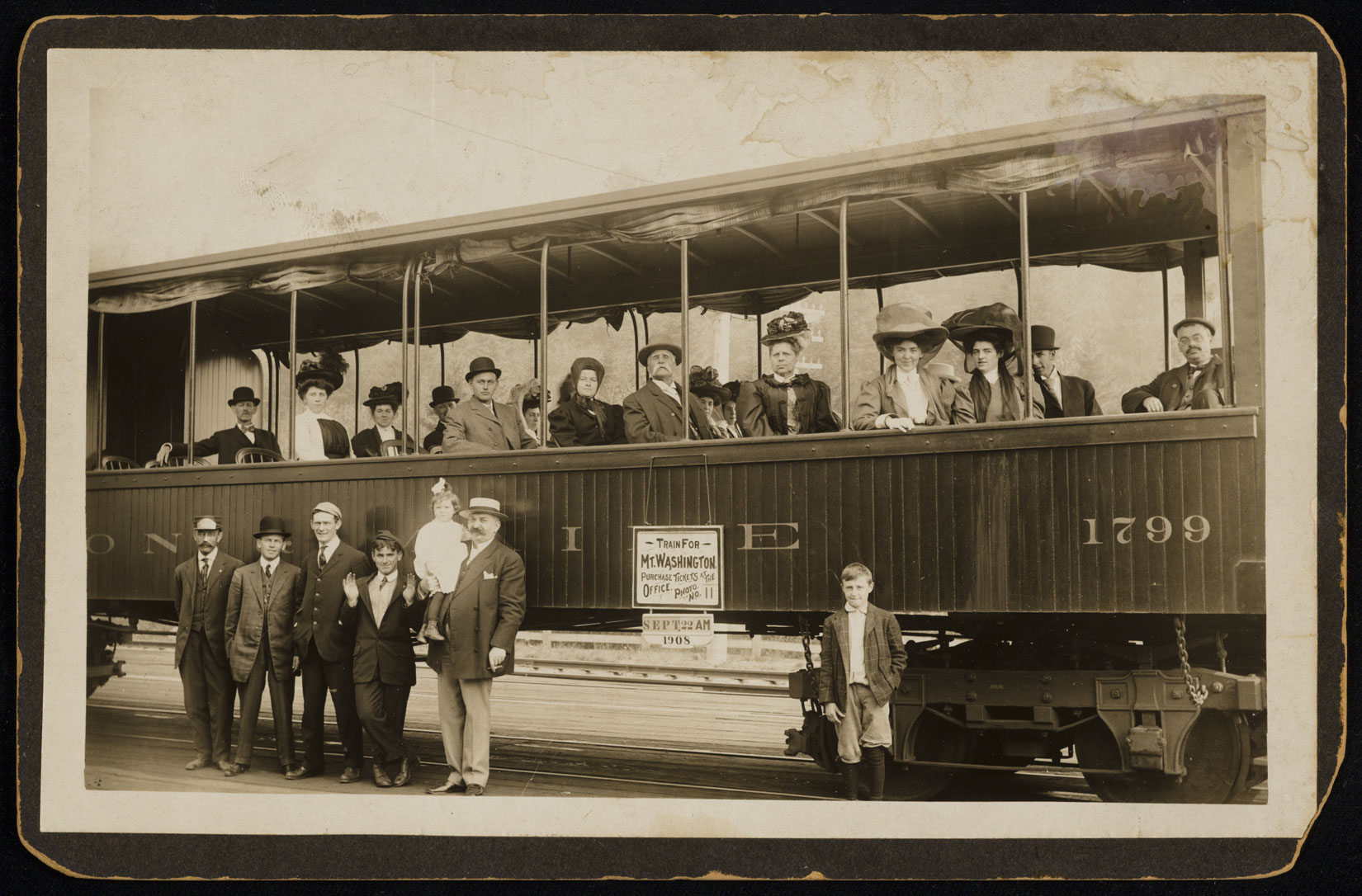 Photo of train with passengers posing next to it and passengers seated inside